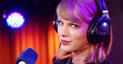 gif of Taylor Swift wearing headphones and nodding happily at the camera