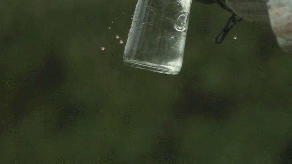 В бутылки стекает вода. Падающий стакан с водой. Стакан падает. Разбивание бутылки с водой.