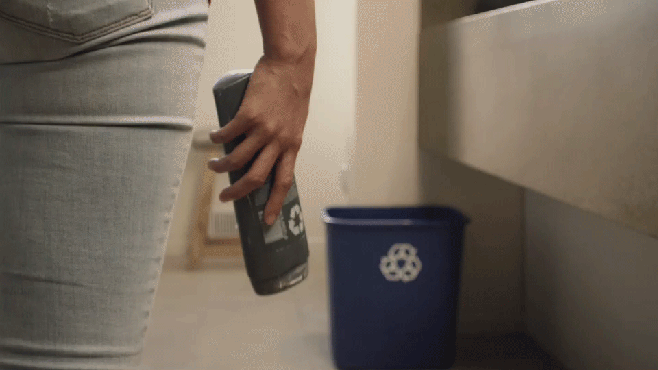 A person tosses a can into a recycle bin.