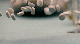 Imagem com diversos comprimidos brancos e redondos caindo numa superfície lisa e azul